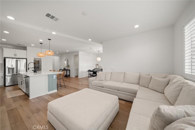 living area featuring recessed lighting, plenty of natural light, and light wood-style flooring