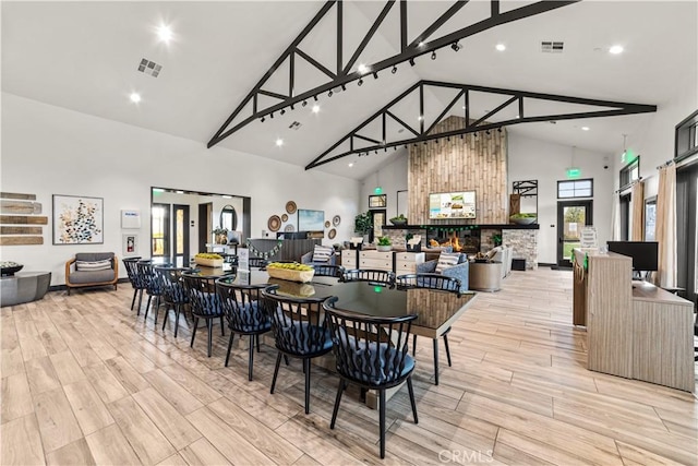 dining area with high vaulted ceiling, light wood finished floors, and recessed lighting