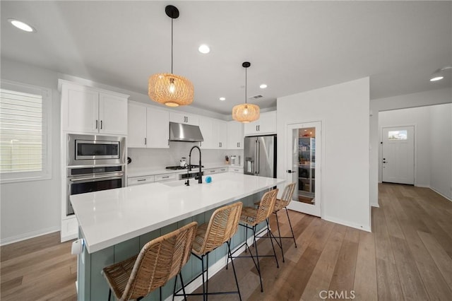 kitchen featuring appliances with stainless steel finishes, under cabinet range hood, baseboards, light wood finished floors, and recessed lighting