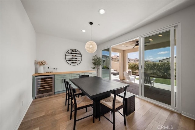 dining room featuring wine cooler, light wood-type flooring, ceiling fan, baseboards, and recessed lighting