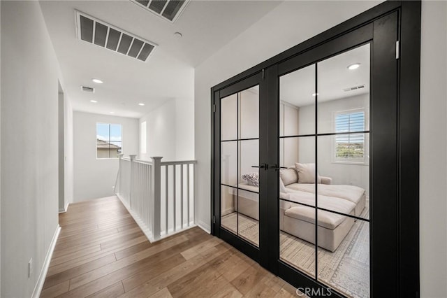 hallway featuring french doors, healthy amount of natural light, wood finished floors, baseboards, and recessed lighting