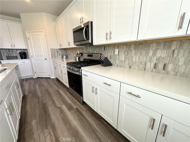 24555 Bravery Cir, Menifee, CA 92584 - kitchen featuring appliances with stainless steel finishes, white cabinetry, tasteful backsplash, light countertops, and dark wood finished floors