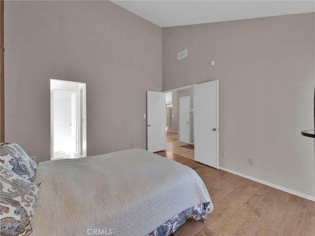bedroom featuring high vaulted ceiling, wood finished floors, and baseboards