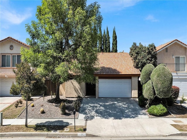 obstructed view of property featuring a tile roof, driveway, stucco siding, and a garage