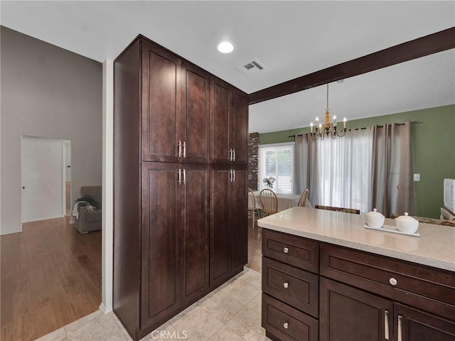 kitchen with a chandelier, light countertops, dark brown cabinets, pendant lighting, and beam ceiling