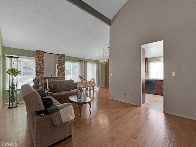living area featuring a chandelier, light wood-style flooring, baseboards, and high vaulted ceiling