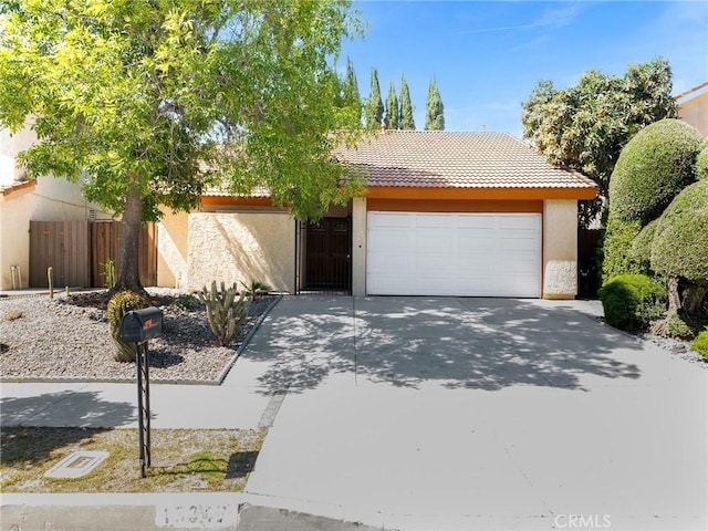 view of property hidden behind natural elements with an attached garage, stucco siding, driveway, and a tiled roof