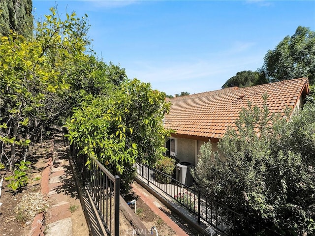 view of side of property with a tile roof, stucco siding, and central AC unit