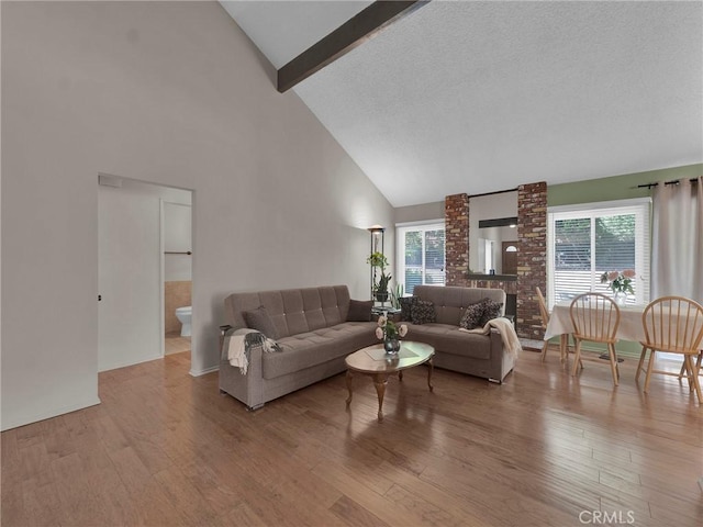 living area with high vaulted ceiling, wood finished floors, beamed ceiling, and healthy amount of natural light