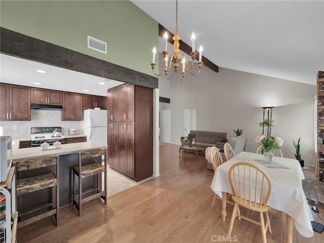 dining space with light wood-style flooring, a chandelier, high vaulted ceiling, and beamed ceiling