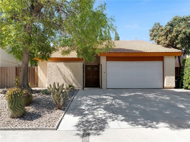 view of front of property featuring stucco siding, a garage, a tiled roof, and driveway