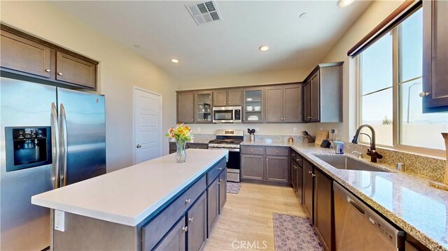 6338 Orion Way, Banning, CA 92220 - kitchen with appliances with stainless steel finishes, a sink, light wood-style flooring, recessed lighting, and glass insert cabinets