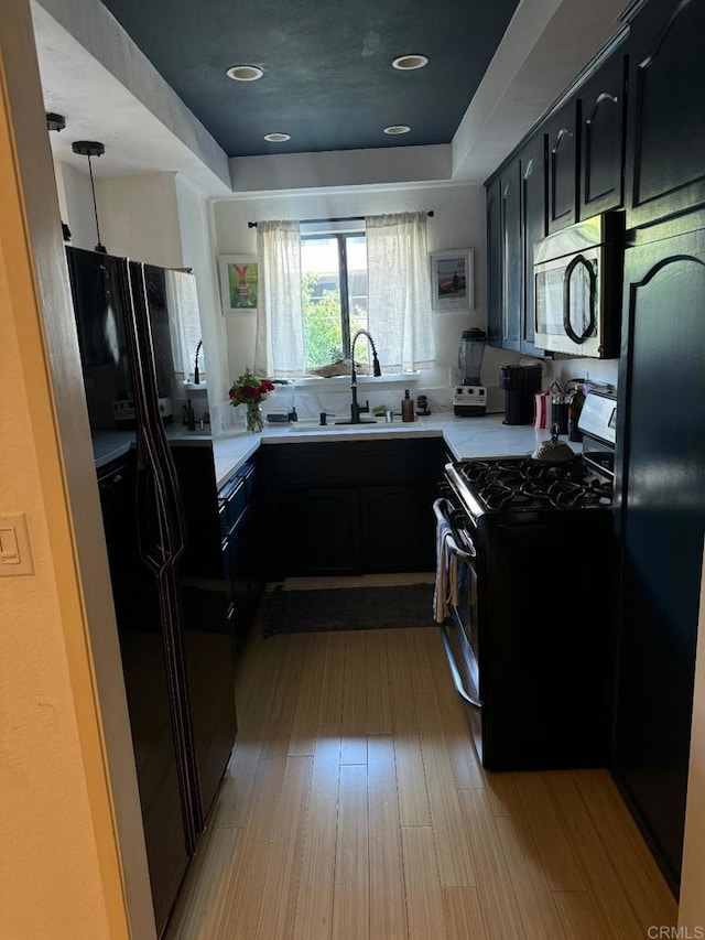 1355 N Sierra Bonita Ave Unit 204, West Hollywood, CA 90046 - kitchen featuring black appliances, a sink, dark cabinets, light countertops, and a tray ceiling