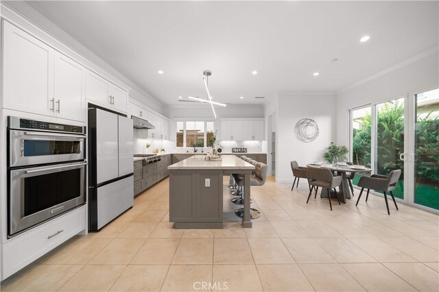 112 Turning Post, Irvine, CA 92620 - kitchen featuring stainless steel appliances, under cabinet range hood, white cabinetry, light tile patterned flooring, and ornamental molding