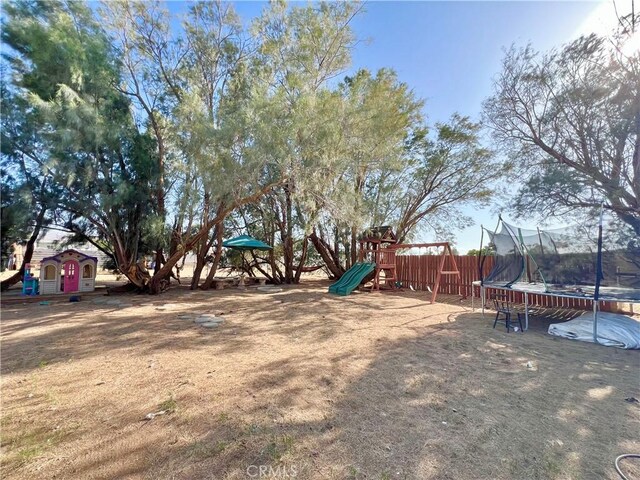 23079 Minnetonka Rd, Apple Valley, CA 92308 - view of yard featuring a trampoline, a playground, and a storage unit