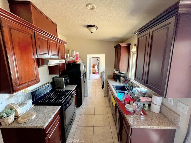 23079 Minnetonka Rd, Apple Valley, CA 92308 - kitchen featuring black range with gas cooktop, a sink, under cabinet range hood, light tile patterned flooring, and a textured ceiling