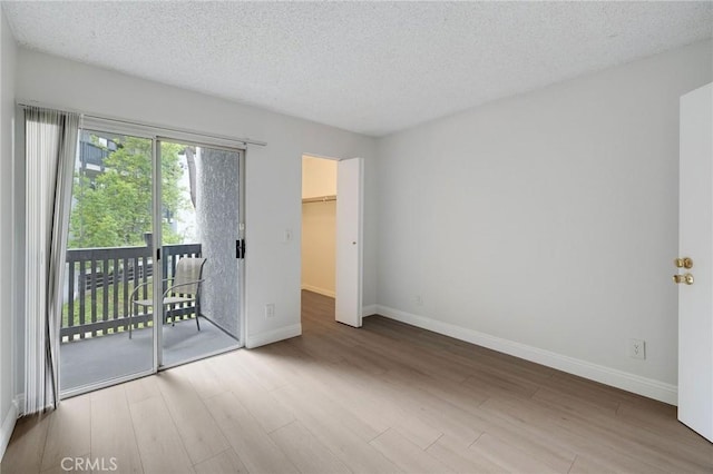 3602 W Estates Ln Unit 306, Rolling Hills Estates, CA 90274 - unfurnished bedroom featuring access to exterior, baseboards, wood finished floors, a textured ceiling, and a spacious closet