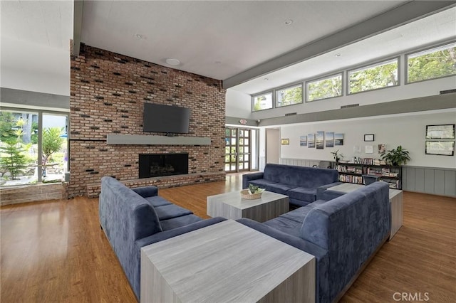 3602 W Estates Ln Unit 306, Rolling Hills Estates, CA 90274 - living room featuring wood finished floors, beam ceiling, high vaulted ceiling, and a brick fireplace