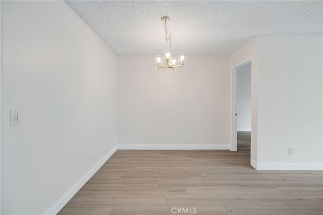 3602 W Estates Ln Unit 306, Rolling Hills Estates, CA 90274 - unfurnished room featuring a chandelier, light wood-style floors, a textured ceiling, and baseboards