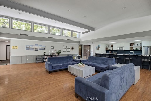 3602 W Estates Ln Unit 306, Rolling Hills Estates, CA 90274 - living area featuring light wood-style floors, a high ceiling, wainscoting, and beamed ceiling