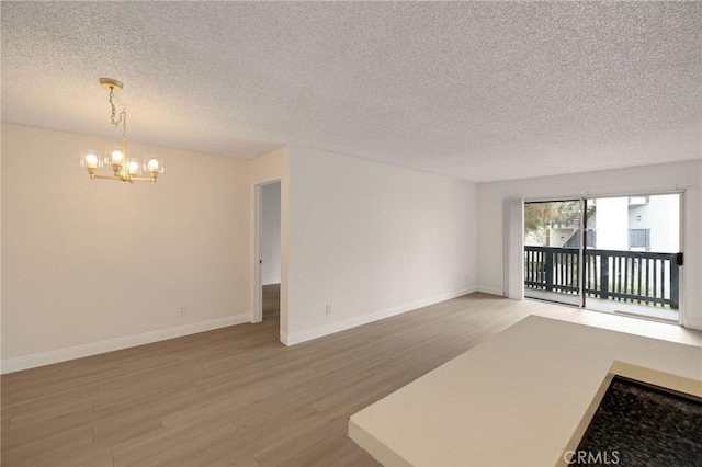3602 W Estates Ln Unit 306, Rolling Hills Estates, CA 90274 - unfurnished living room featuring a chandelier, light wood-type flooring, a textured ceiling, and baseboards