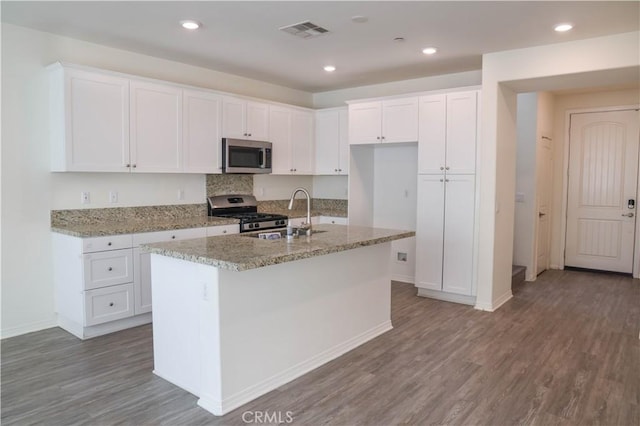 13936 Blossom Way, Eastvale, CA 92880 - kitchen with appliances with stainless steel finishes, a sink, wood finished floors, white cabinets, and recessed lighting