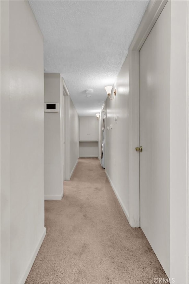 560 E Mountain View St, Barstow, CA 92311 - corridor with light colored carpet, baseboards, washer / clothes dryer, and a textured ceiling