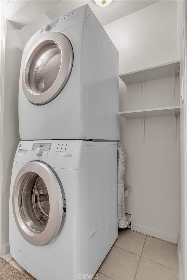560 E Mountain View St, Barstow, CA 92311 - clothes washing area featuring stacked washing machine and dryer, light tile patterned flooring, and baseboards