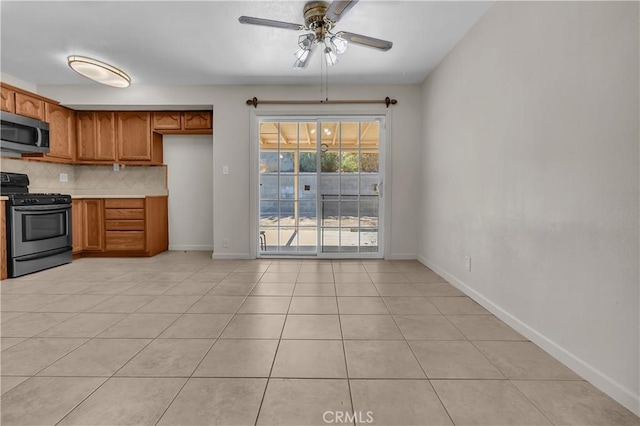 560 E Mountain View St, Barstow, CA 92311 - kitchen featuring appliances with stainless steel finishes, brown cabinetry, tasteful backsplash, a ceiling fan, and baseboards