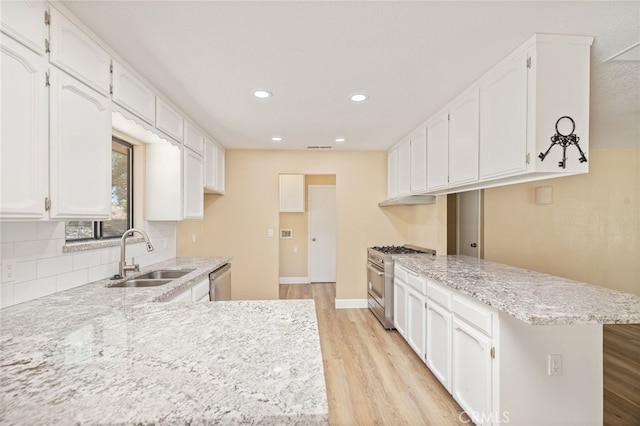 42490 Ranger Circle Way, Coarsegold, CA 93614 - kitchen with stainless steel appliances, a sink, a peninsula, light wood-style flooring, and backsplash