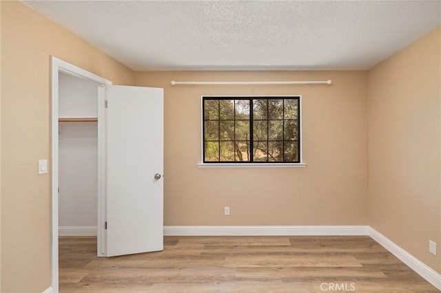 42490 Ranger Circle Way, Coarsegold, CA 93614 - unfurnished bedroom with light wood-type flooring, a spacious closet, baseboards, a textured ceiling, and a closet