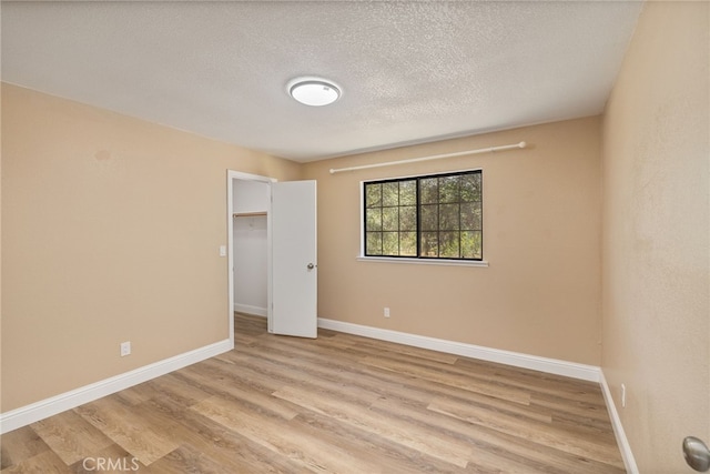 42490 Ranger Circle Way, Coarsegold, CA 93614 - unfurnished bedroom with light wood finished floors, baseboards, a textured ceiling, a spacious closet, and a closet