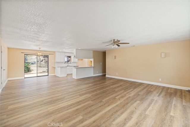 42490 Ranger Circle Way, Coarsegold, CA 93614 - unfurnished living room featuring light wood-style floors, ceiling fan, baseboards, a textured ceiling, and a chandelier