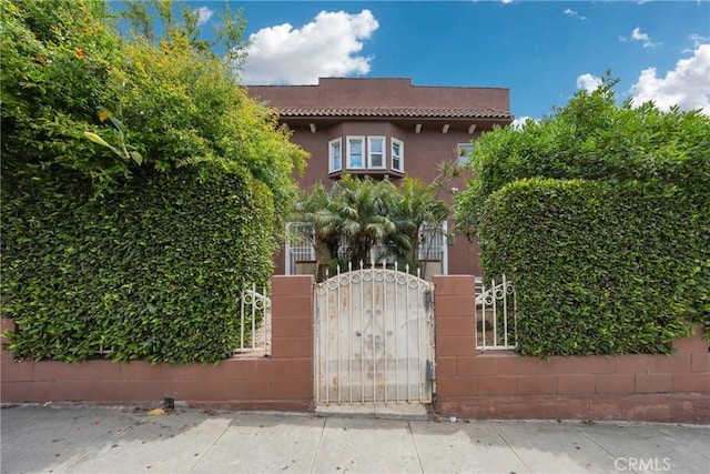 2006 S Harcourt Ave, Los Angeles, CA 90016 - view of front of house with a gate, a tile roof, and stucco siding