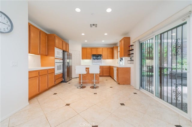15752 Mimosa Ct, Fontana, CA 92336 - kitchen featuring white appliances, light countertops, a kitchen breakfast bar, light tile patterned floors, and recessed lighting