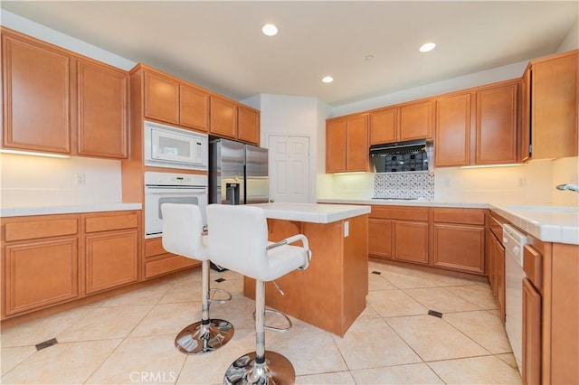 15752 Mimosa Ct, Fontana, CA 92336 - kitchen featuring white appliances, a kitchen breakfast bar, backsplash, recessed lighting, and light countertops