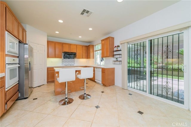 15752 Mimosa Ct, Fontana, CA 92336 - kitchen with white appliances, light countertops, a kitchen breakfast bar, a kitchen island, and recessed lighting