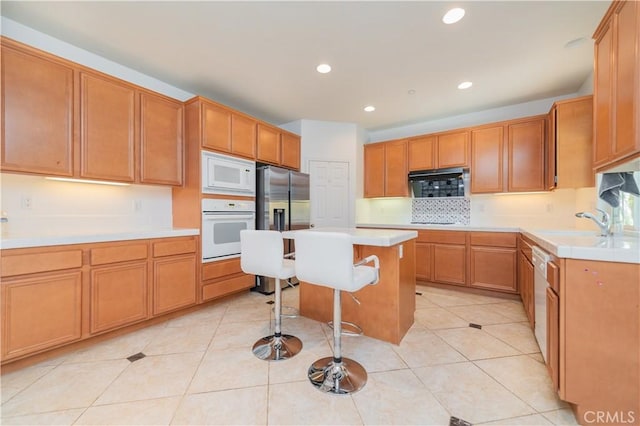 15752 Mimosa Ct, Fontana, CA 92336 - kitchen with white appliances, a kitchen bar, tasteful backsplash, light countertops, and recessed lighting