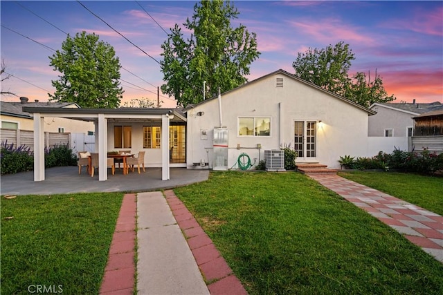 back of property at dusk with central AC, stucco siding, and a patio area