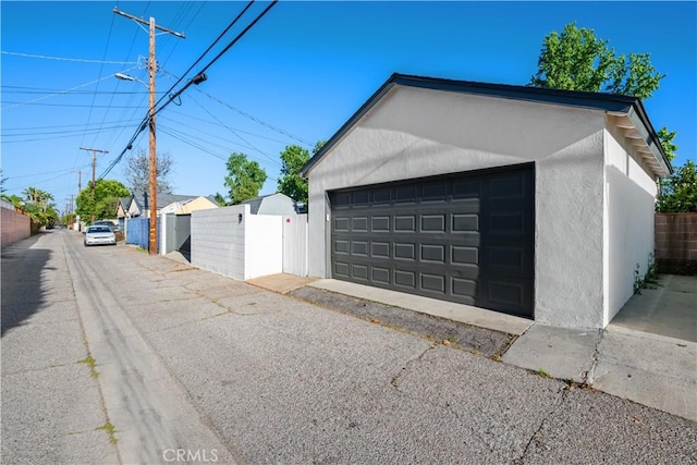 detached garage featuring fence and a gate