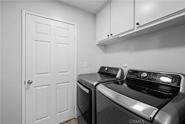 laundry room featuring cabinet space, washing machine and clothes dryer, and light wood-style flooring