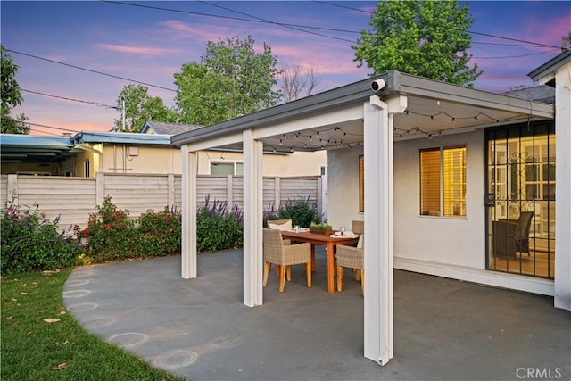 patio terrace at dusk with fence and outdoor dining space