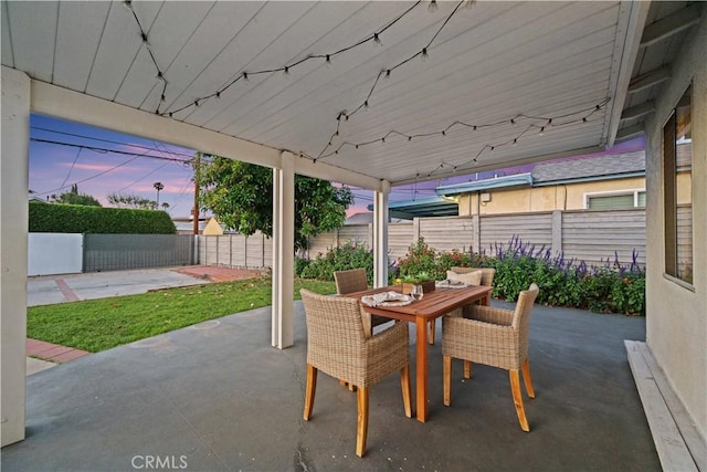 patio terrace at dusk with a fenced backyard and outdoor dining space