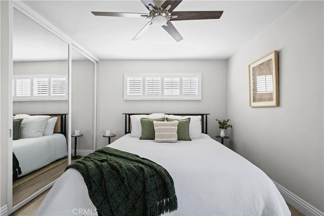 bedroom with ceiling fan, wood finished floors, and baseboards
