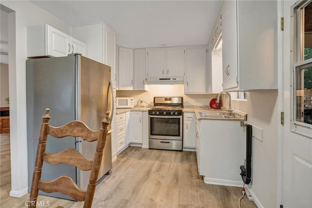 32159 Cove Cir, Running Springs, CA 92382 - kitchen with appliances with stainless steel finishes, a sink, under cabinet range hood, light wood-type flooring, and light countertops