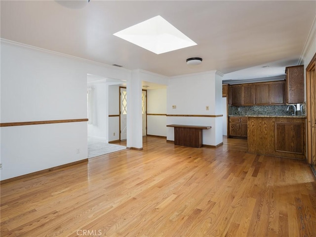 1715 W Santa Cruz St, San Pedro, CA 90732 - unfurnished living room with a skylight, crown molding, light wood-type flooring, a sink, and baseboards