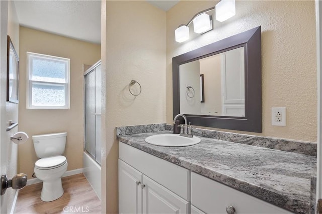 253 Gurnsey Dr, Red Bluff, CA 96080 - full bathroom featuring wood finished floors, vanity, toilet, a textured wall, and baseboards