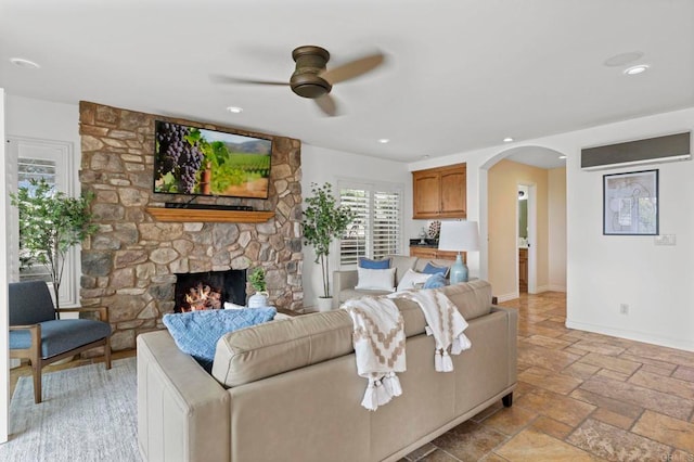 515 S Sierra Ave Unit 130, Solana Beach, CA 92075 - living room featuring arched walkways, a ceiling fan, stone tile floors, baseboards, and a fireplace