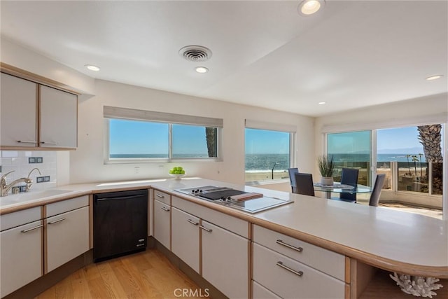 7335 Vista Del Mar Ln, Playa Del Rey, CA 90293 - kitchen with black dishwasher, a sink, stovetop with downdraft, light wood-style flooring, and light countertops