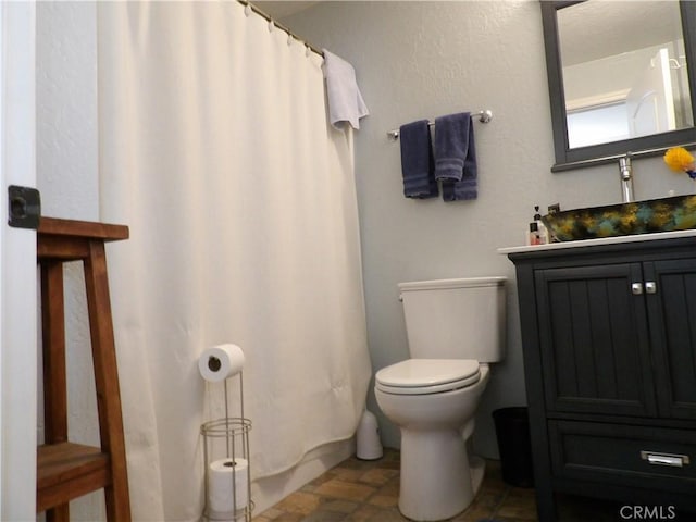 bathroom with toilet, vanity, and a shower with shower curtain
